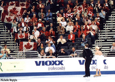 Shae-Lynn Bourne &amp; Victor Kraatz (CAN) skate past Canadian fans while waiting for their names to be called before the CD