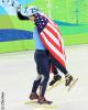 Apolo Ohno celebrates with a flag-wrapped JR Celski